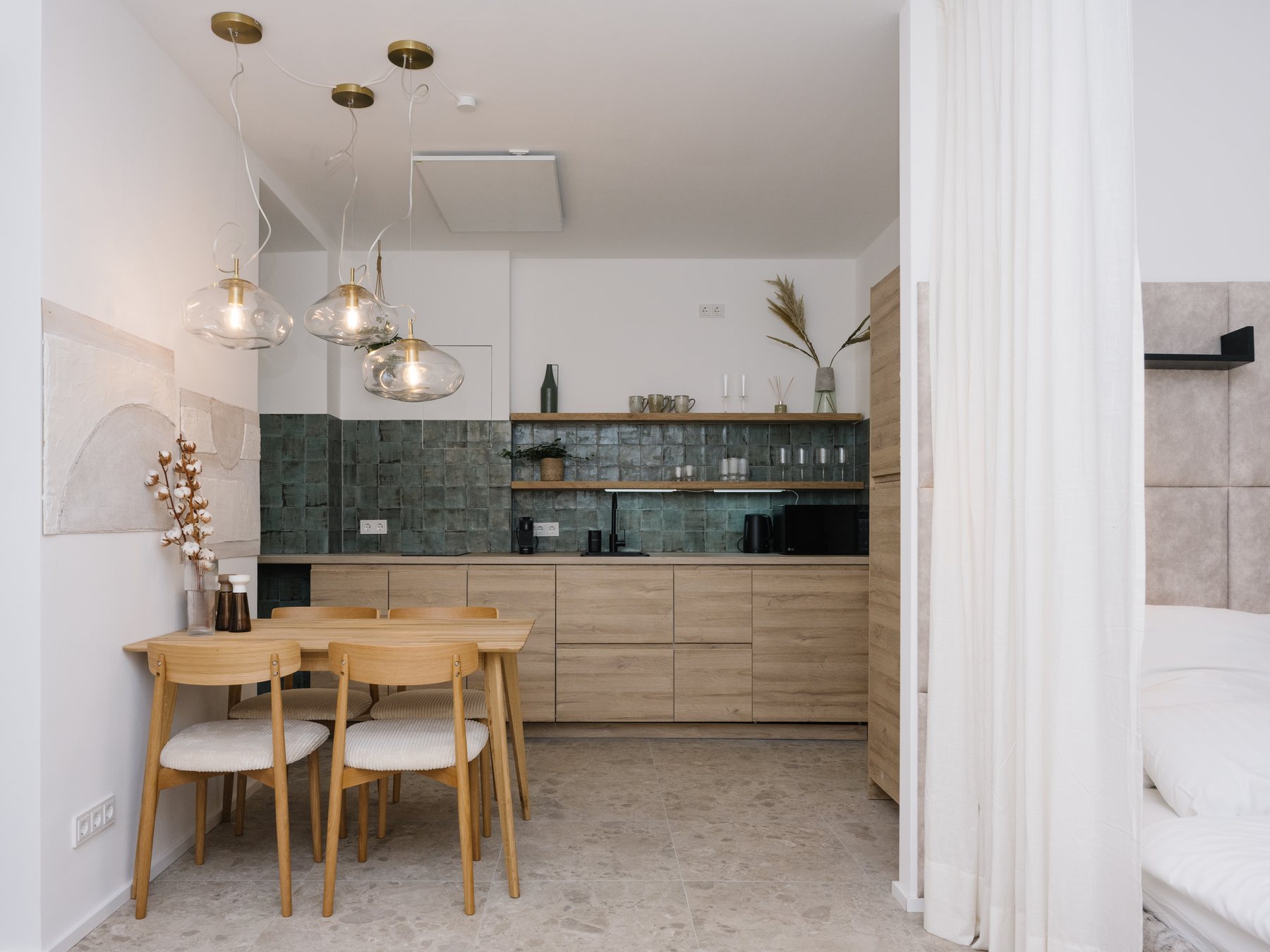 Sanierte Küche mit grünen Wandfliesen, Holzfronten und Essplatz am Fenster